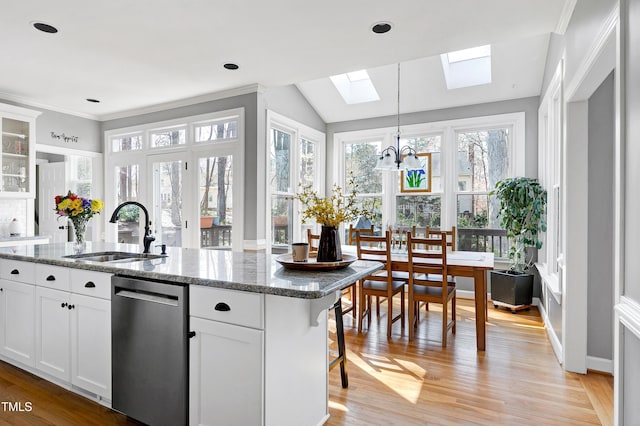 kitchen featuring a sink, a chandelier, dark stone counters, light wood-type flooring, and stainless steel dishwasher