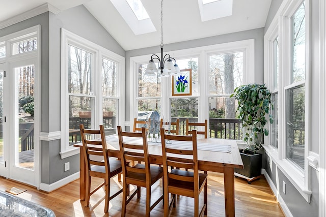 sunroom featuring lofted ceiling with skylight and an inviting chandelier