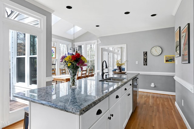 kitchen featuring wood finished floors, dark stone counters, a sink, white cabinets, and dishwasher