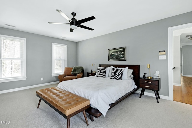 bedroom with multiple windows, light colored carpet, visible vents, and baseboards