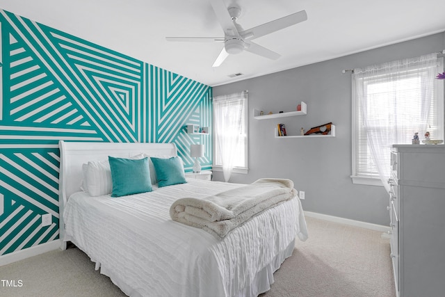 carpeted bedroom with visible vents, wallpapered walls, baseboards, ceiling fan, and an accent wall