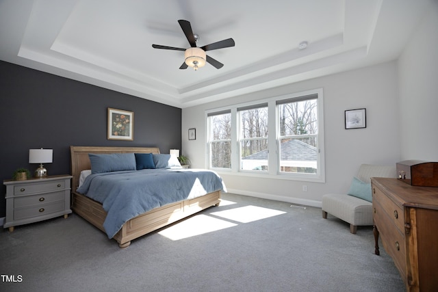 carpeted bedroom with a tray ceiling, baseboards, visible vents, and ceiling fan