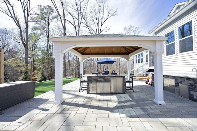 view of patio featuring a gazebo, outdoor wet bar, area for grilling, and a hot tub