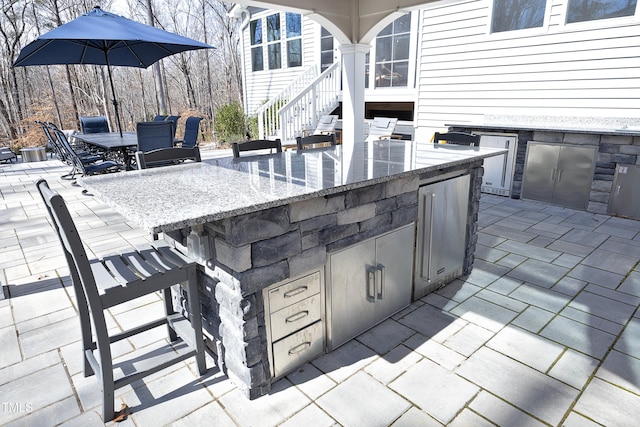 view of patio / terrace featuring exterior kitchen, outdoor dining area, and outdoor dry bar