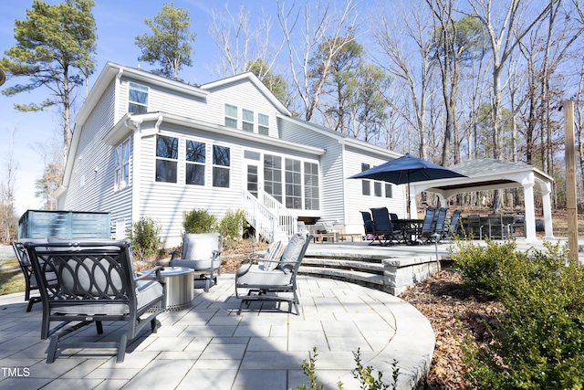 back of property featuring outdoor dining area, a patio area, and a sunroom