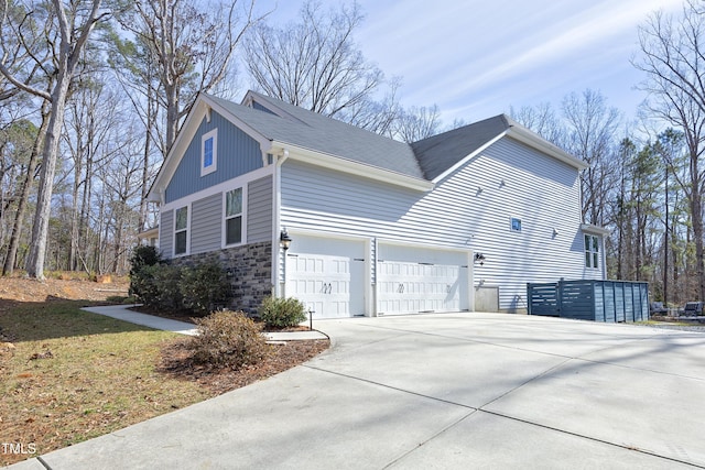 view of side of property featuring concrete driveway and stone siding