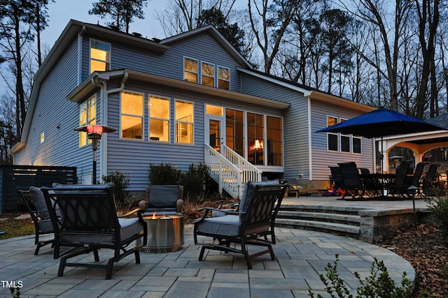 rear view of house featuring a fire pit and a patio area