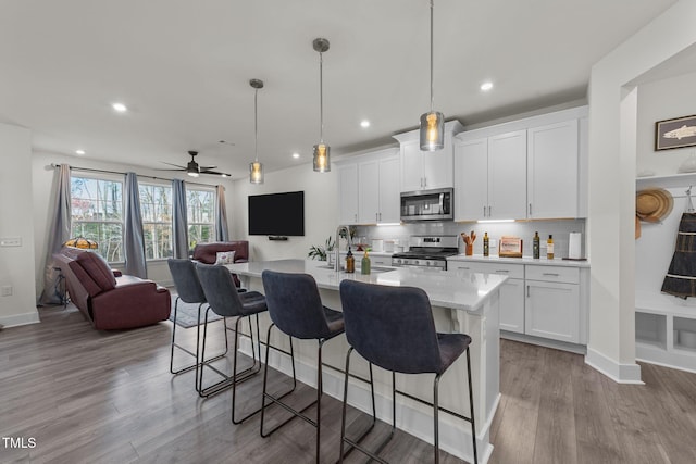 kitchen featuring decorative backsplash, a kitchen breakfast bar, open floor plan, stainless steel appliances, and a sink