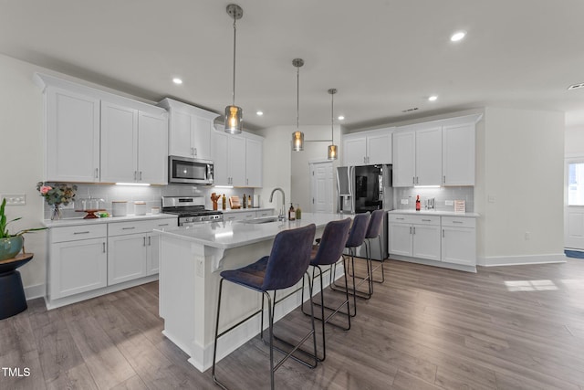 kitchen featuring stainless steel appliances, a sink, a kitchen bar, and wood finished floors