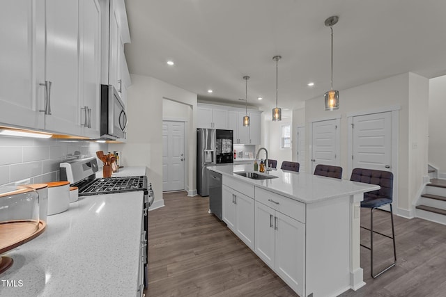 kitchen with appliances with stainless steel finishes, white cabinets, a sink, and dark wood-type flooring