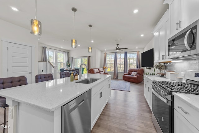 kitchen featuring a sink, a kitchen breakfast bar, open floor plan, appliances with stainless steel finishes, and decorative backsplash