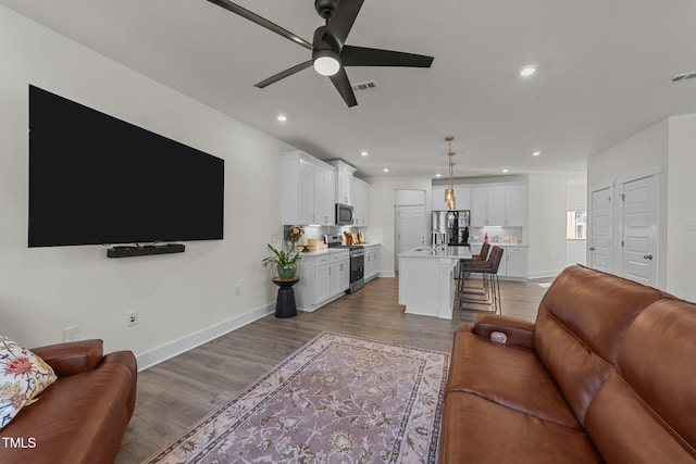 living area with baseboards, light wood finished floors, a ceiling fan, and recessed lighting