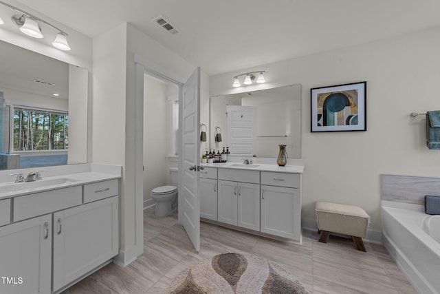 full bath with a garden tub, visible vents, two vanities, and a sink