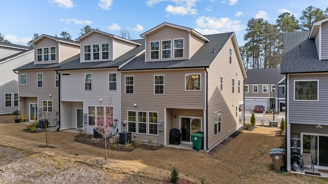 rear view of property with central AC unit and roof with shingles