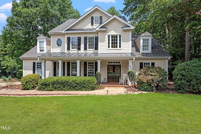 view of front facade with metal roof, a porch, french doors, a standing seam roof, and a front yard