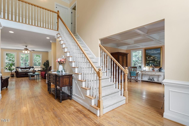 stairs with plenty of natural light, wood-type flooring, coffered ceiling, and beam ceiling