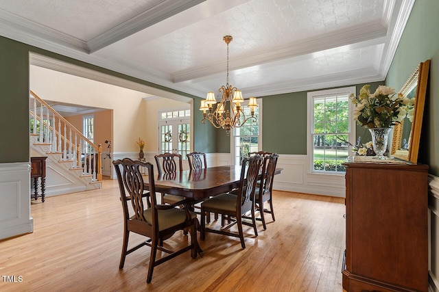 dining room featuring a wainscoted wall, light wood-style flooring, stairway, crown molding, and a notable chandelier