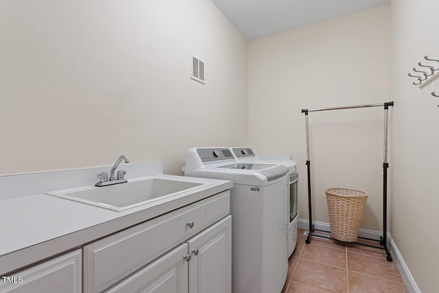 clothes washing area with cabinet space, light tile patterned floors, visible vents, separate washer and dryer, and a sink