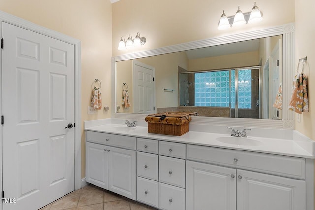 full bathroom featuring double vanity, a tile shower, a sink, and tile patterned floors