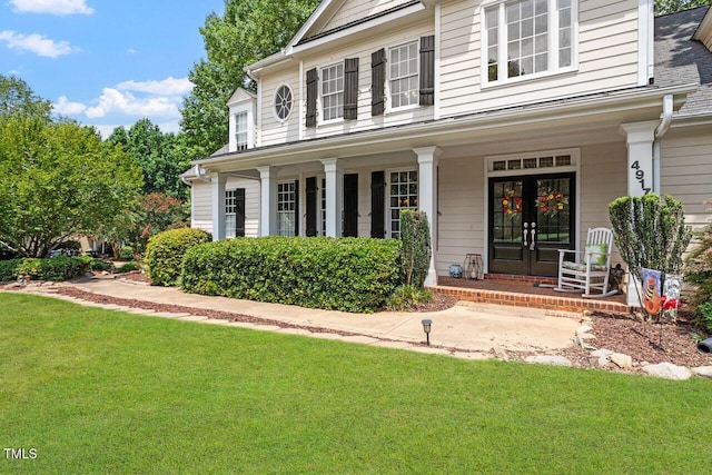 view of front of property featuring covered porch, french doors, and a front yard