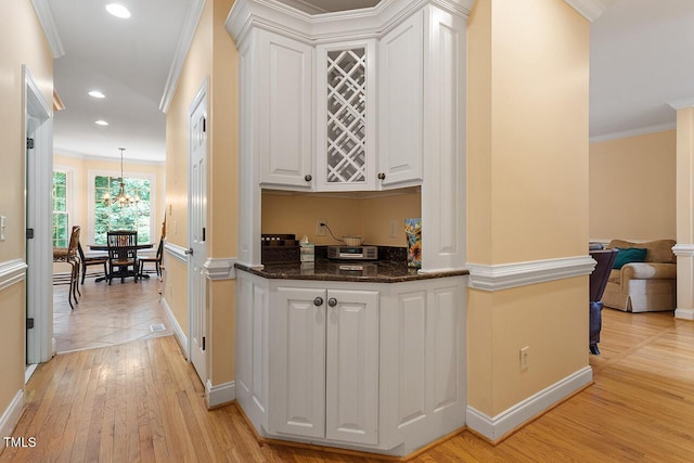 hallway featuring recessed lighting, light wood-style flooring, an inviting chandelier, ornamental molding, and baseboards