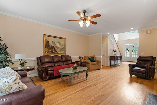 living area featuring light wood finished floors, baseboards, ceiling fan, crown molding, and french doors