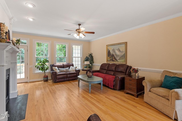 living room with a ceiling fan, light wood-type flooring, crown molding, and a premium fireplace