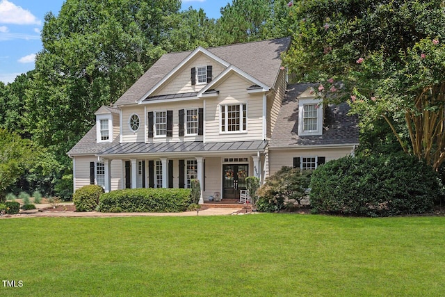 view of front of property with a standing seam roof, metal roof, a front lawn, and roof with shingles