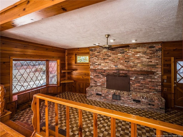 interior space featuring a textured ceiling, wood walls, and a ceiling fan