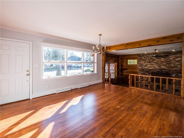 unfurnished living room featuring a notable chandelier, baseboards, and wood finished floors