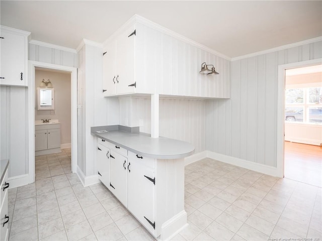 kitchen with light countertops, white cabinetry, crown molding, and baseboards