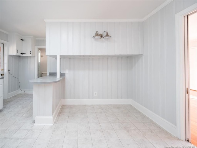 kitchen with light countertops, ornamental molding, white cabinetry, a peninsula, and baseboards