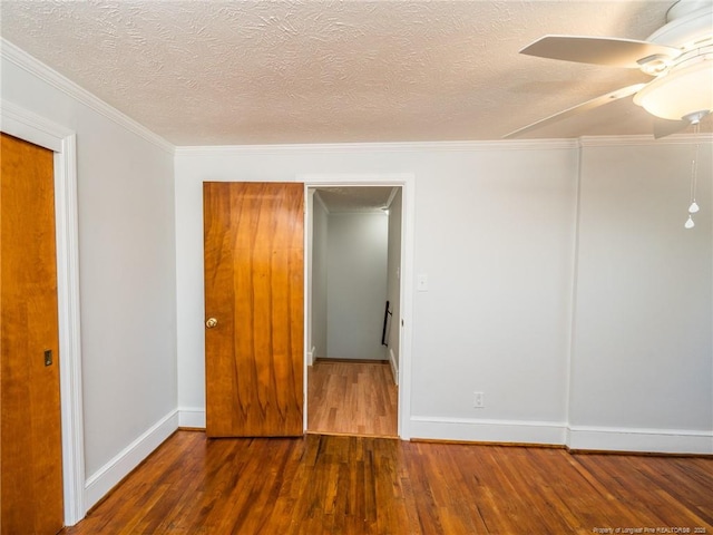 spare room with baseboards, a ceiling fan, ornamental molding, wood finished floors, and a textured ceiling