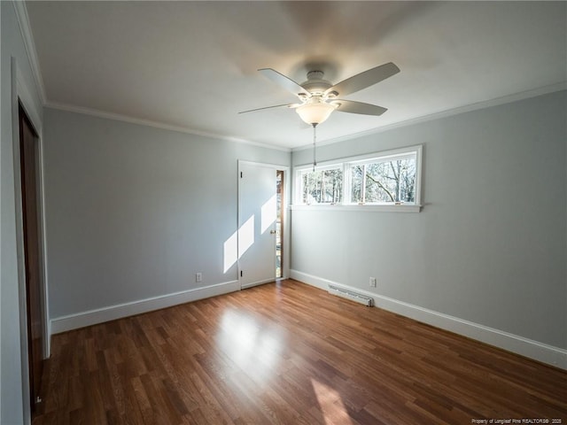 empty room featuring crown molding, wood finished floors, visible vents, and baseboards