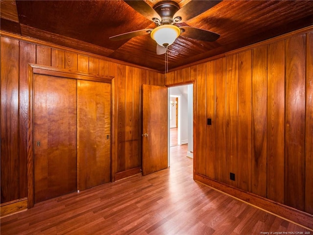 spare room featuring ceiling fan, wood walls, wooden ceiling, and wood finished floors