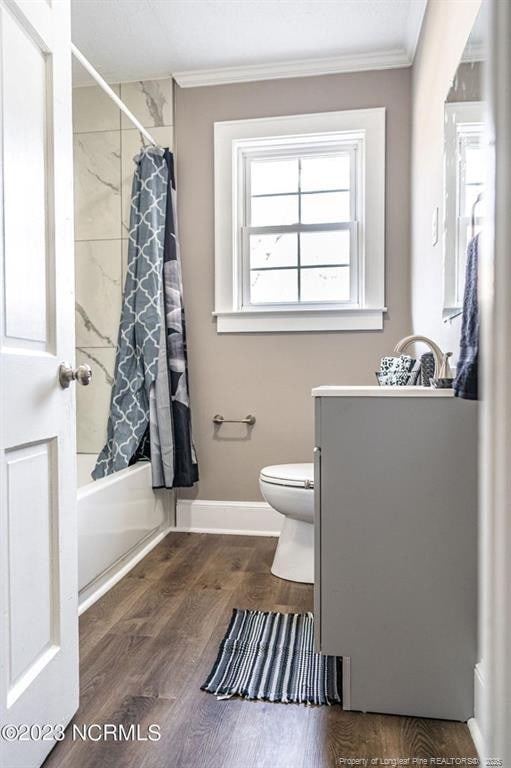 full bath featuring toilet, wood finished floors, vanity, ornamental molding, and shower / bath combo