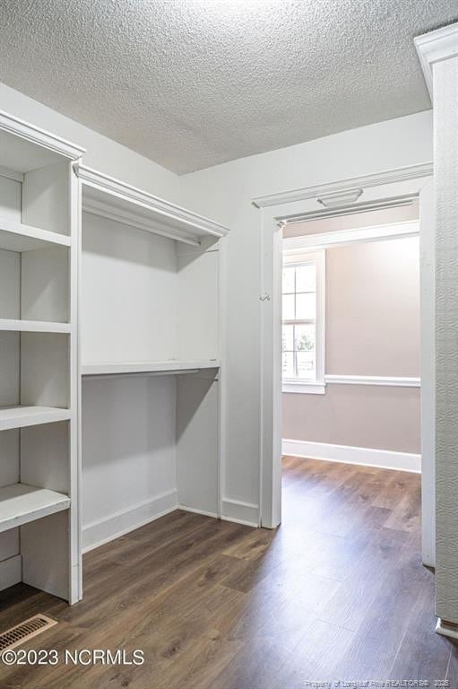 spacious closet with dark wood-style flooring and visible vents