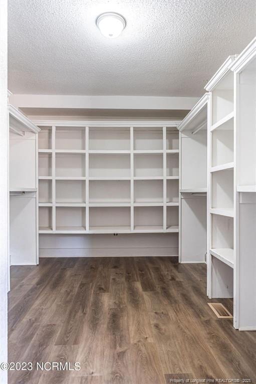 spacious closet with dark wood-style floors and visible vents