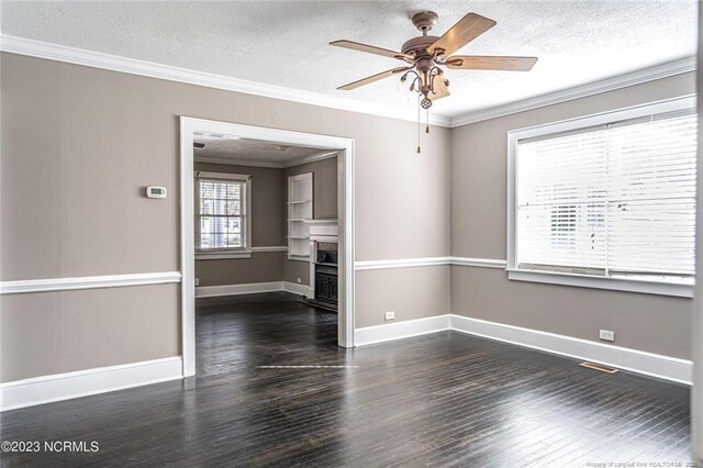 unfurnished room with dark wood-style floors, ornamental molding, a fireplace, and baseboards