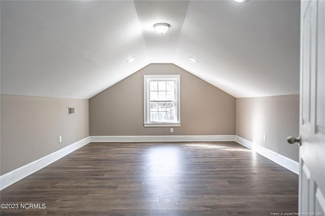 additional living space featuring lofted ceiling, baseboards, visible vents, and dark wood finished floors