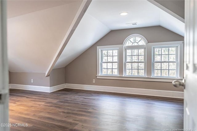 bonus room with dark wood-style floors, visible vents, baseboards, and vaulted ceiling