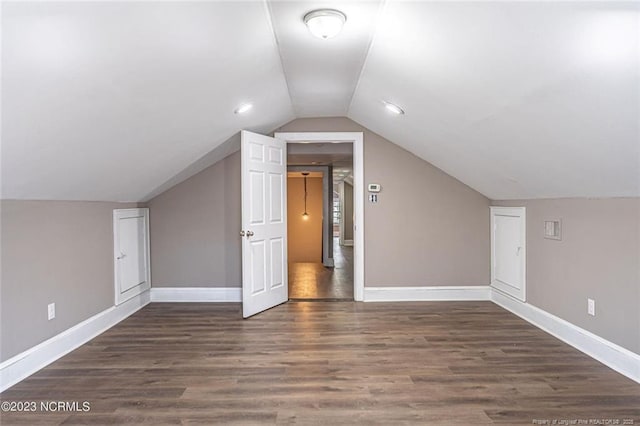 bonus room with lofted ceiling, baseboards, and dark wood-style flooring