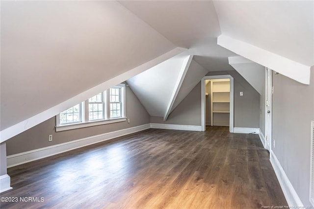 additional living space with vaulted ceiling, dark wood finished floors, and baseboards