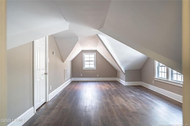 additional living space with dark wood-style floors, lofted ceiling, and baseboards