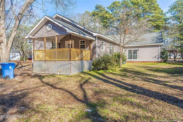 back of property featuring covered porch and a yard