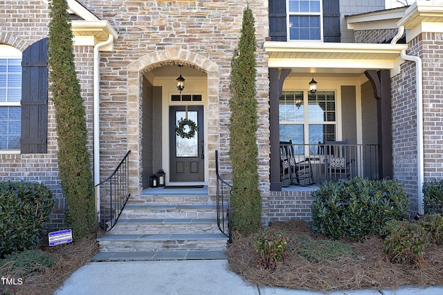 property entrance featuring covered porch and brick siding