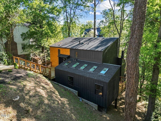 back of house featuring a shingled roof and a wooden deck