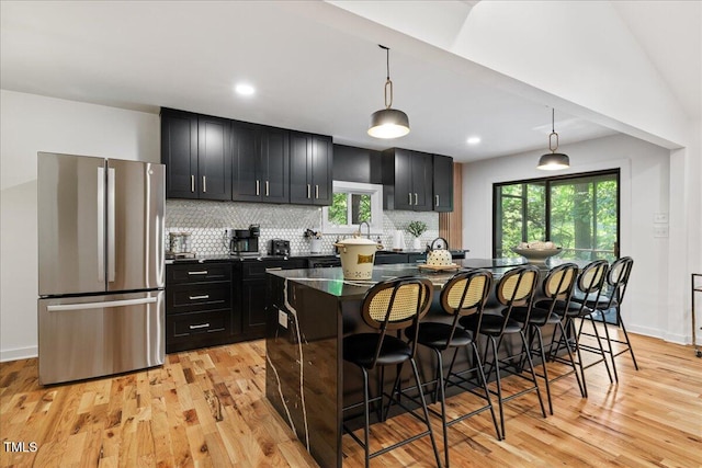 kitchen featuring decorative light fixtures, a kitchen island, freestanding refrigerator, and a kitchen breakfast bar