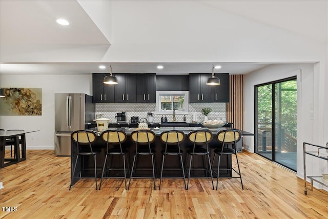 kitchen featuring hanging light fixtures, a kitchen breakfast bar, and freestanding refrigerator