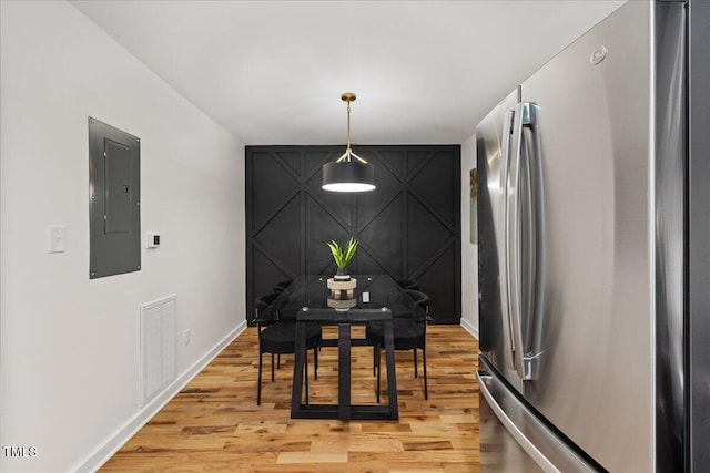 dining space featuring baseboards, light wood-type flooring, visible vents, and electric panel